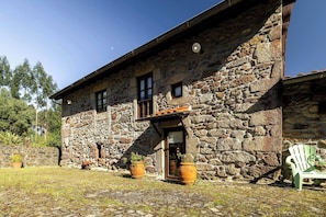 A stone building with a wooden door, two windows, and a small balcony.