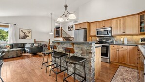A modern kitchen with a stone island, bar stools, and wooden cabinets.