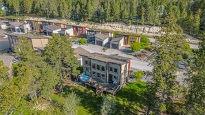 Un edificio moderno de varios pisos con piscina, rodeado de un bosque denso y montañas.