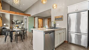 Una cocina moderna con una isla central, electrodomésticos de acero inoxidable y una zona de comedor con mesa y sillas.