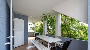 A patio with a white table and benches, a black chair, and a door.