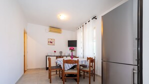 A dining area with a table, chairs, a refrigerator, and a TV on the wall. - Apartments Valy 6 Center Novalja (Novalja)