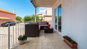 A balcony with a wicker sofa, a small table, and potted plants. - Apartments Valy 6 Center Novalja (Novalja)