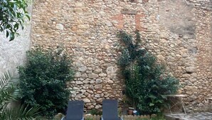 A stone wall with two empty lounge chairs in front.