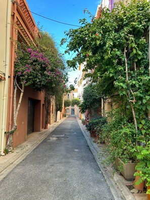 Una calle estrecha bordeada de edificios con balcones y plantas en macetas.