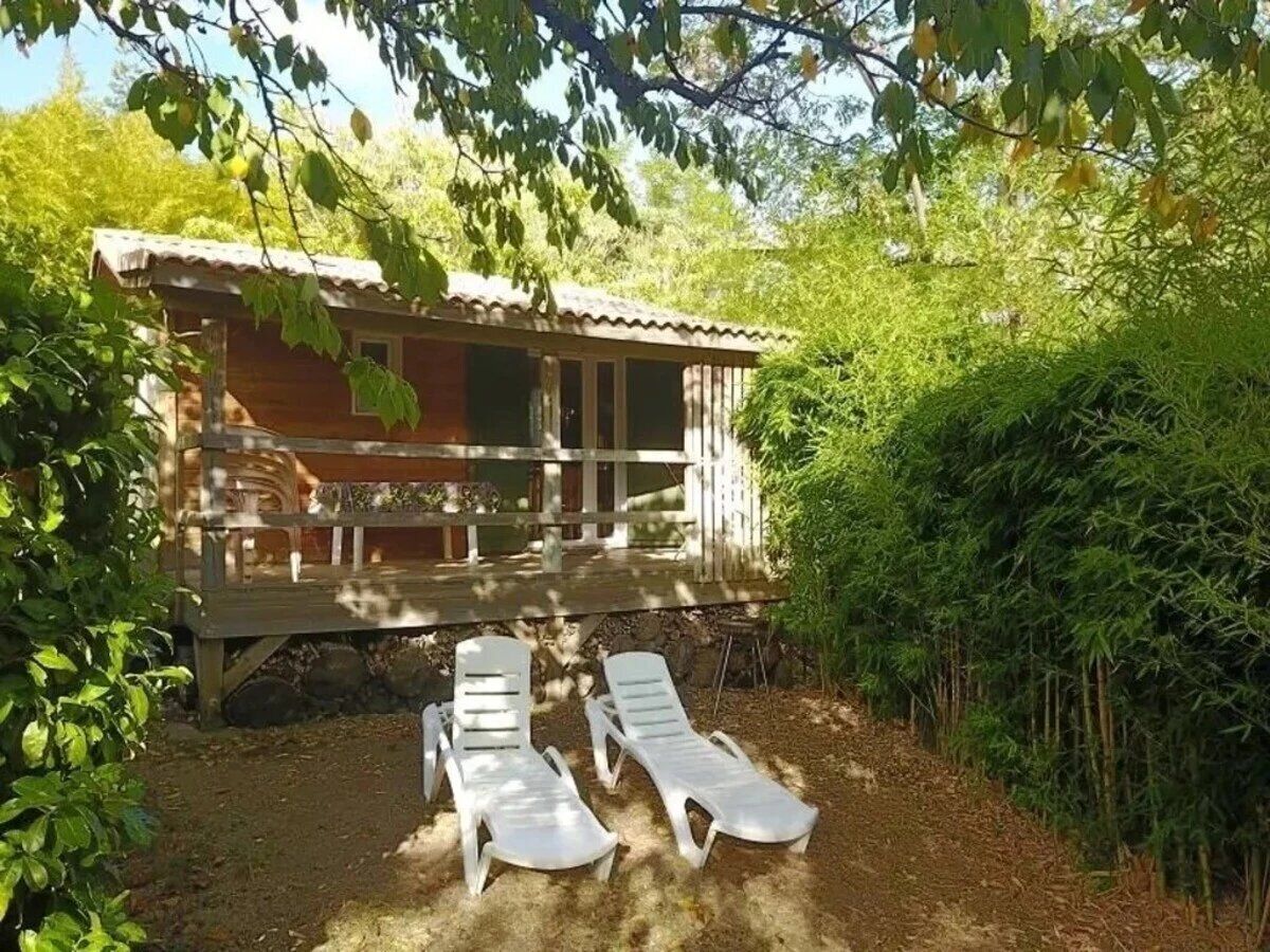 Une cabane en bois avec une véranda et deux fauteuils blancs devant.