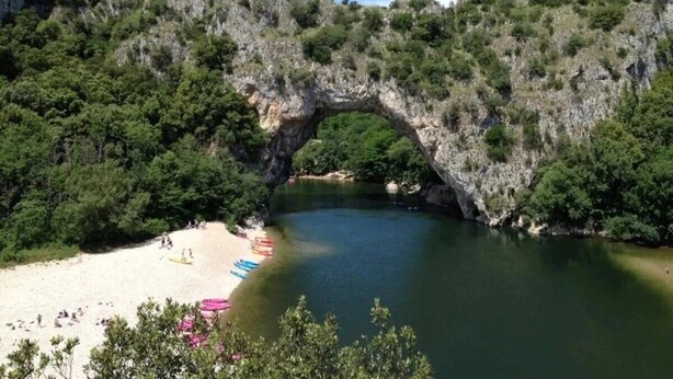 A natural rock arch over a beach with kayaks and people. - ZEcamping 3 étoiles pataugeoire pet friendly animations chalet 22m2 5 pers (Darbres)