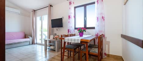 A dining area with a table, chairs, a TV, and a sofa.