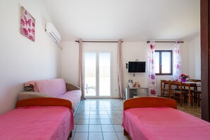 Een kamer met twee bedden, een bureau, een stoel, een televisie en een raam met gordijnen.