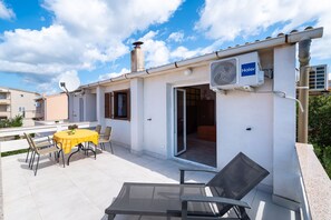 Een terras buiten met een tafel en stoelen, een schuifdeur en een Haier airconditioning.
