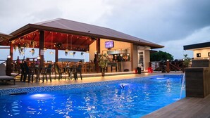 Un bar junto a la piscina con asientos al aire libre y una alberca.
