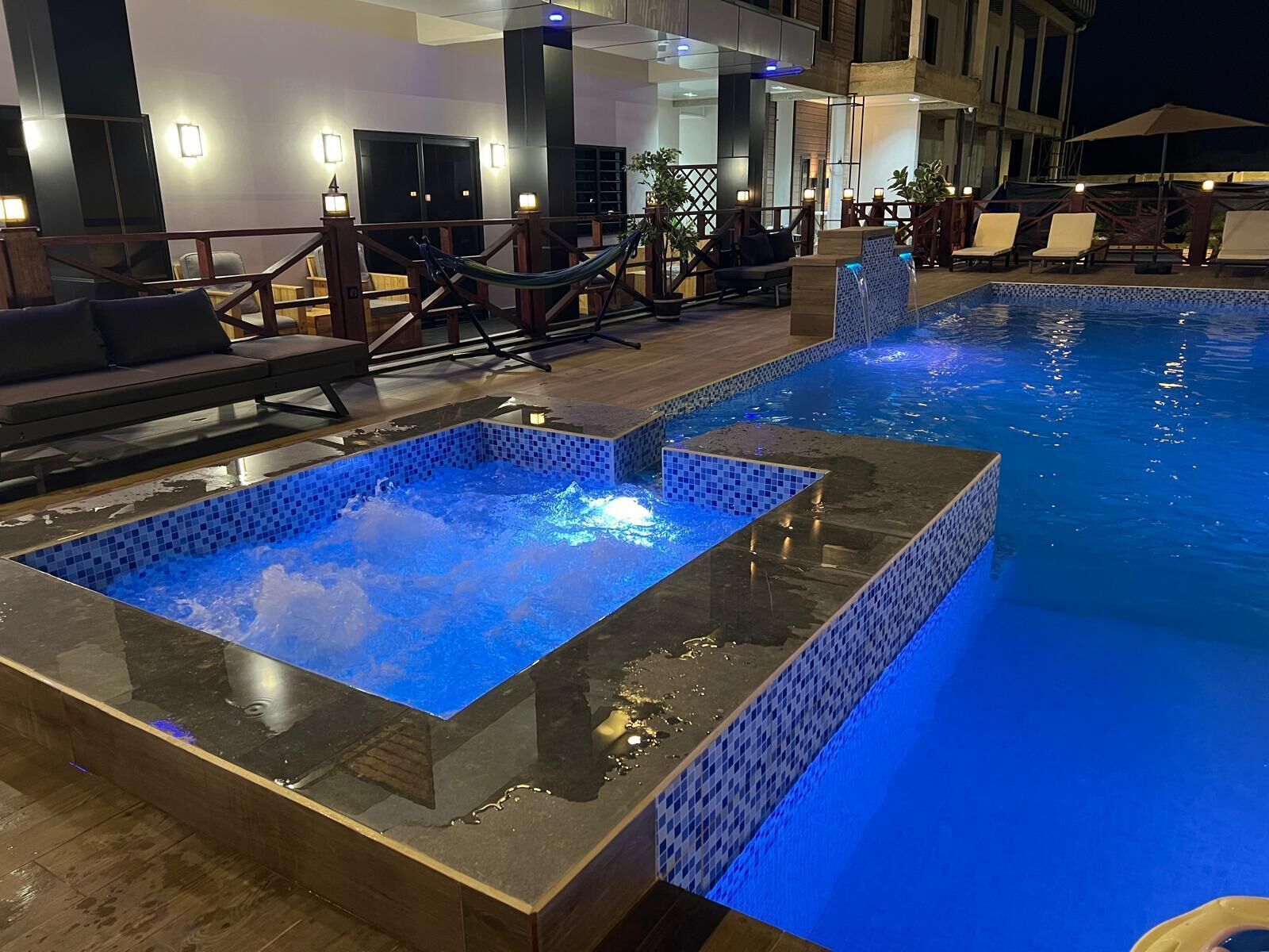 Une piscine dotée d’un jacuzzi à fond de verre, de chaises longues et d’une terrasse en bois.