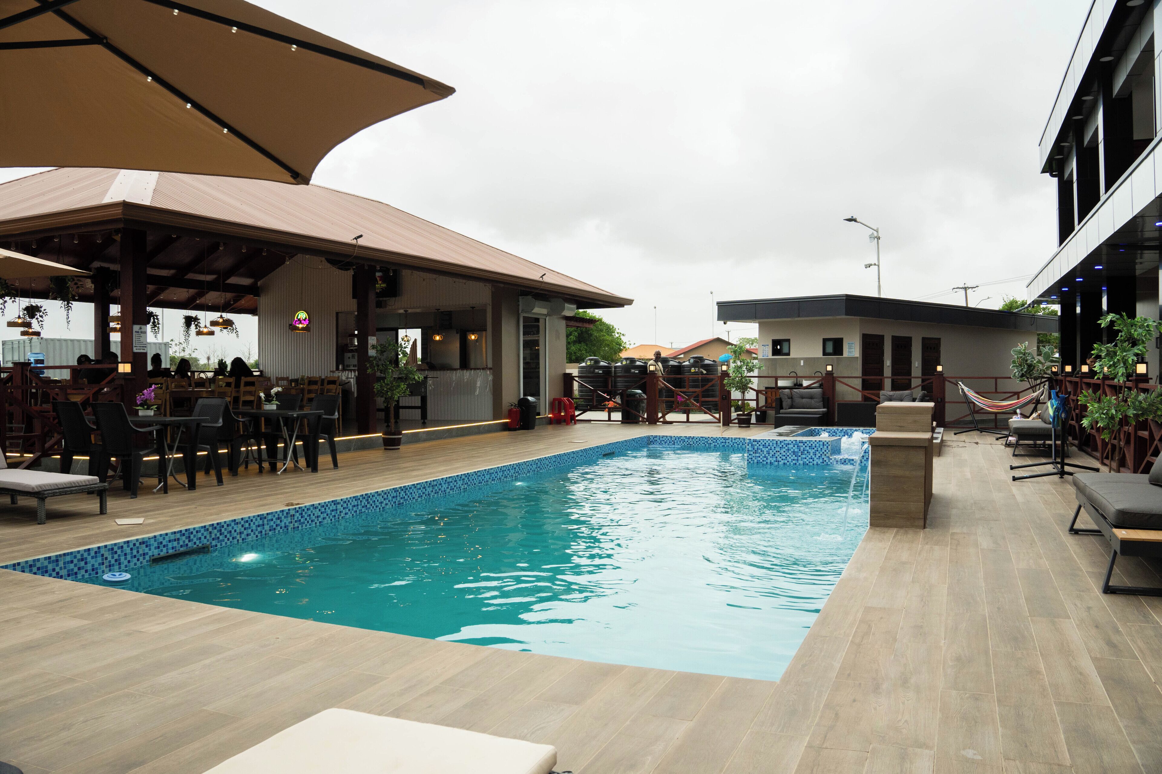 A swimming pool with lounge chairs and a covered seating area.