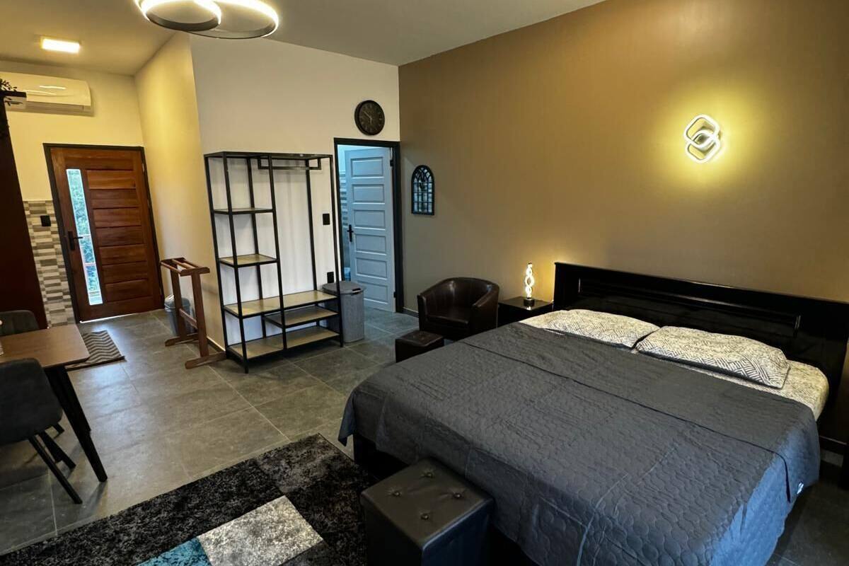 Ein modernes Schlafzimmer mit einem großen Bett, einem Schreibtisch und einem Stuhl. Es gibt einen Kleiderschrank, eine Uhr und eine Wandleuchte.