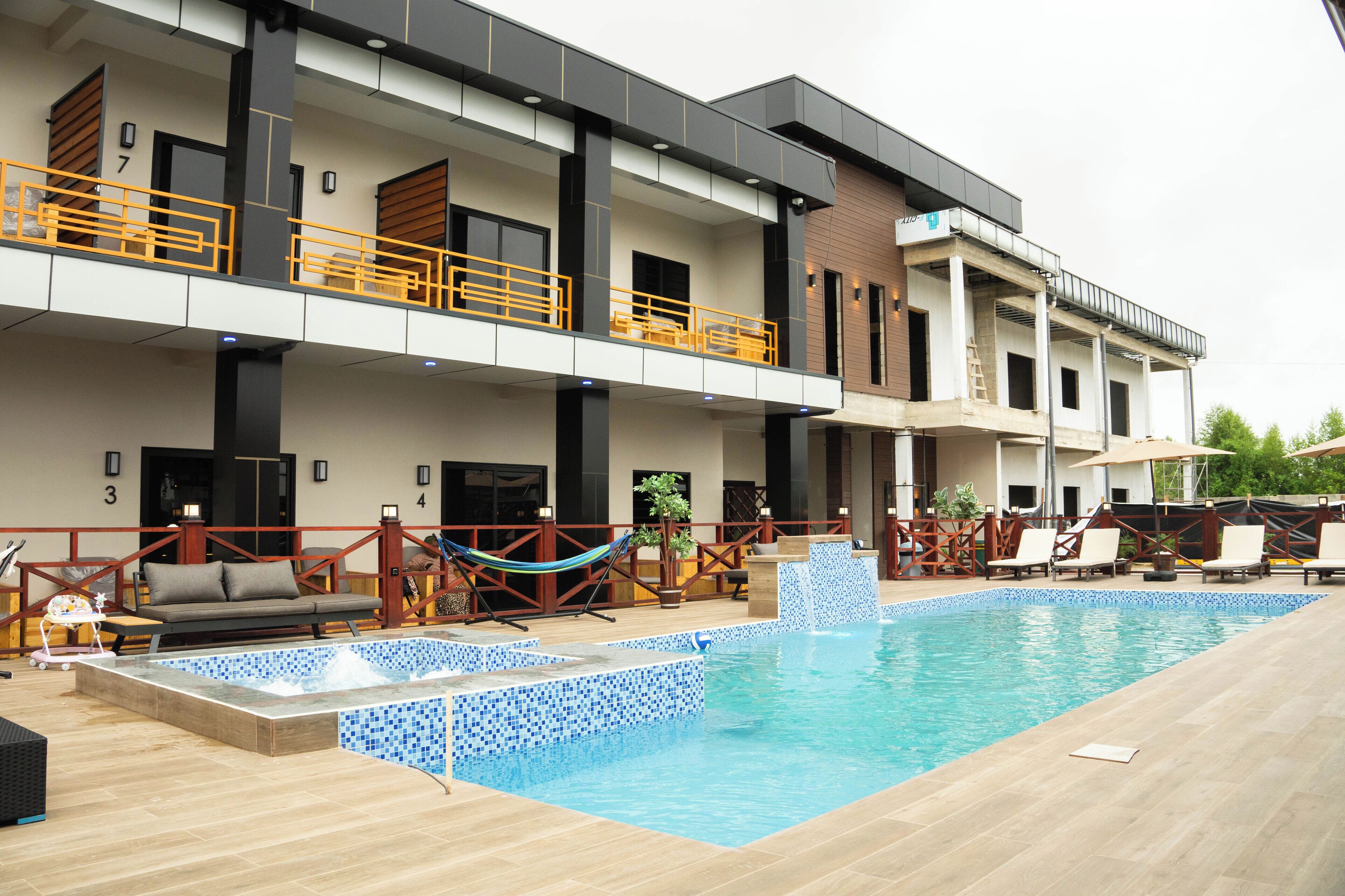 Un hotel moderno con piscina en la azotea, zona de estar exterior y estructura de varios pisos.