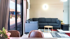 Una sala moderna con un sofá gris, una mesita de centro de madera y una alfombra roja y gris.