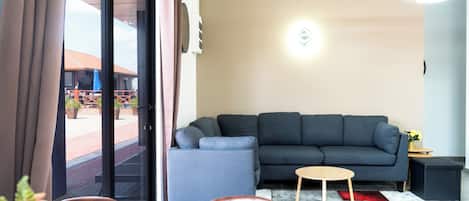 Una sala moderna con un sofá gris, una mesita de centro de madera y una alfombra roja y gris.