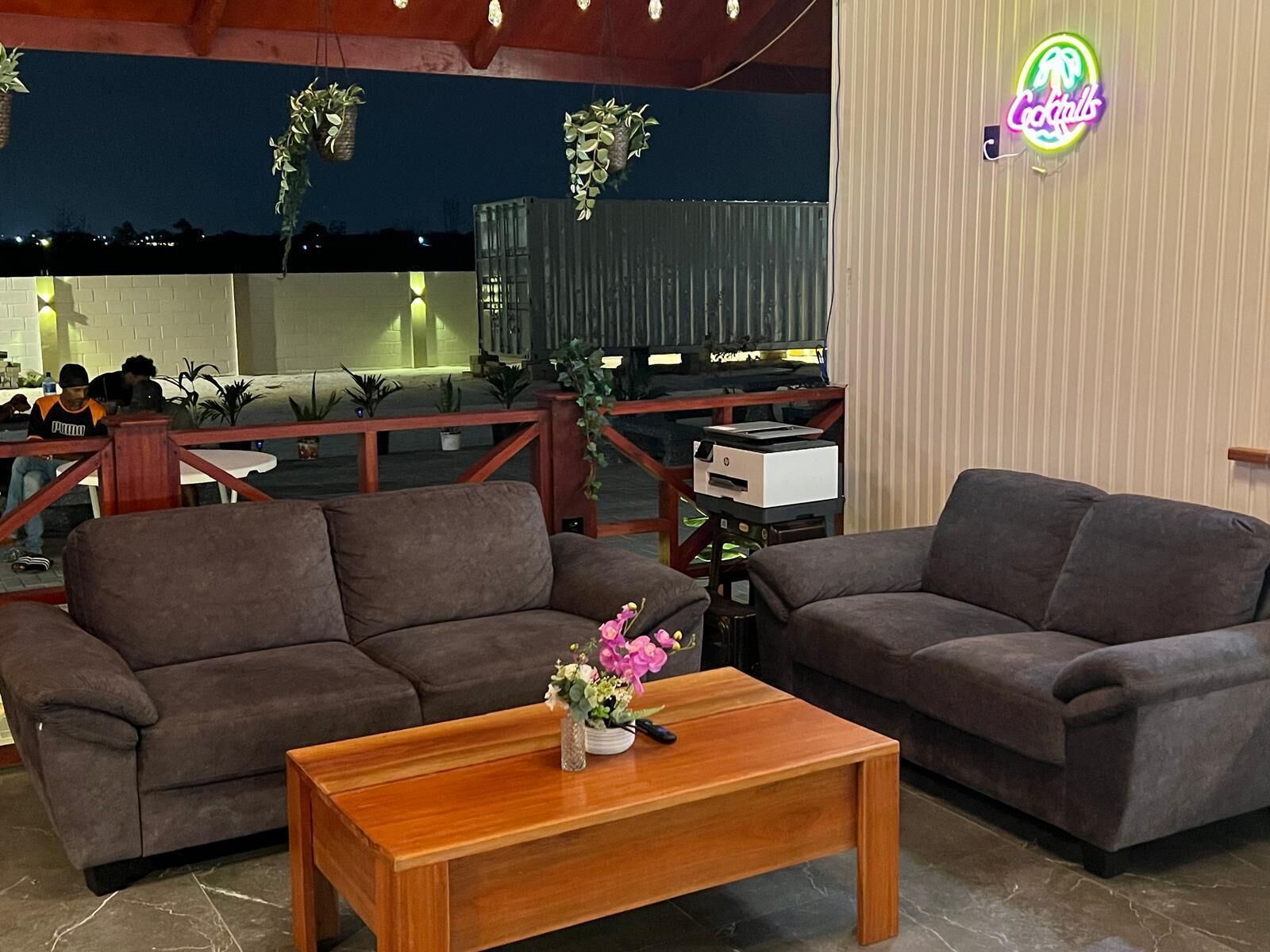 A cozy indoor seating area with two sofas and a wooden coffee table, featuring a small vase of flowers.