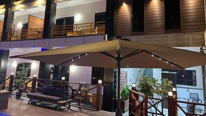 A modern building with a rooftop bar area featuring outdoor seating and a large umbrella. - Yasmin Luxury Resort (Paramaribo)