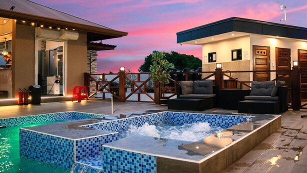 A rooftop pool area with a hot tub, lounge chairs, and a view of the sunset. - Yasmin Luxury Resort (Paramaribo)
