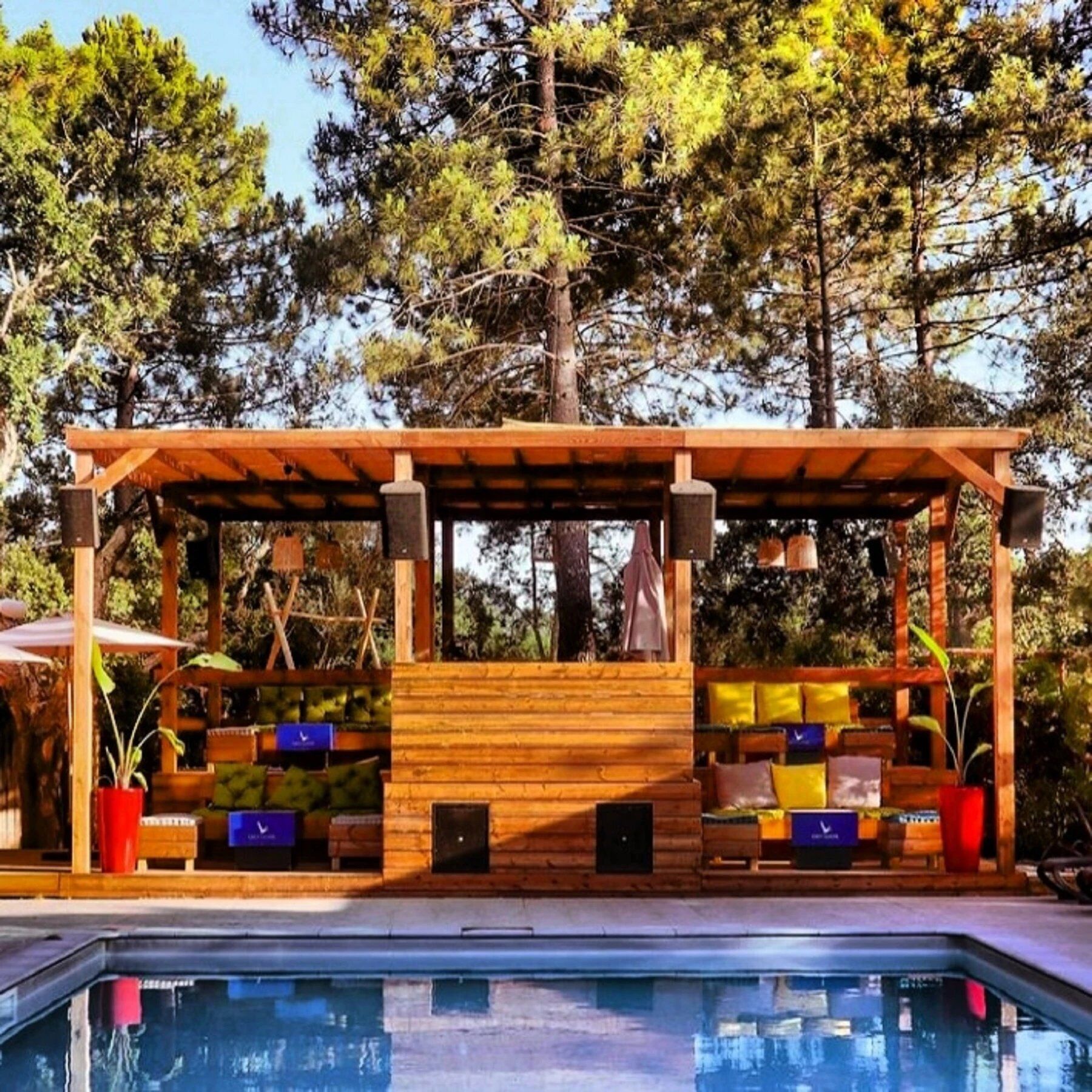 A wooden pergola with a pool in the foreground.