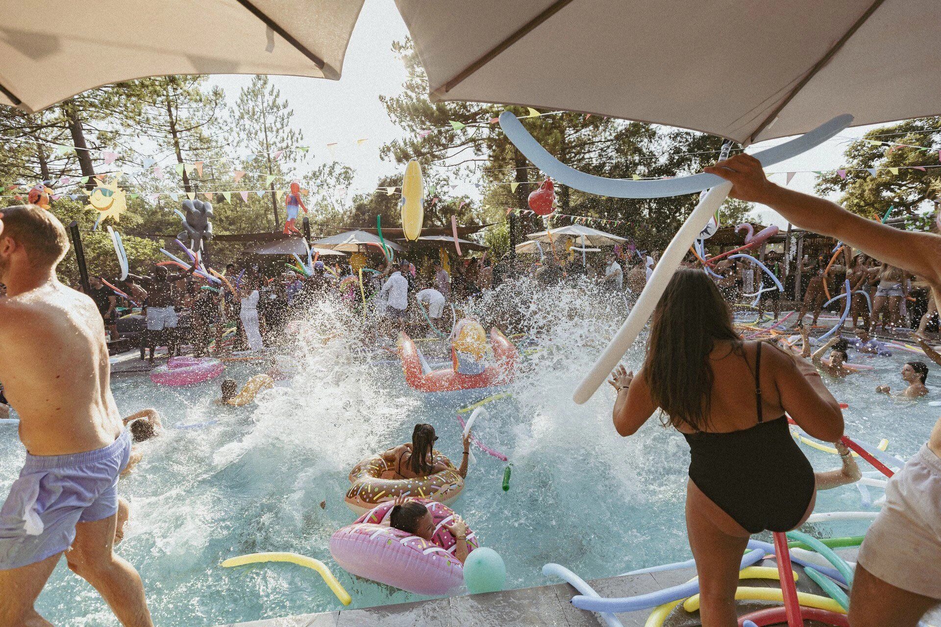 An outdoor pool area with inflatable toys and people enjoying the water.