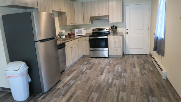 A compact kitchen with a stainless steel refrigerator, microwave, and double oven. Light wood cabinets and a granite countertop are present. - 4 Bdr/2 Bath-Interior Alaska-Moose Creek , North Pole. Minutes from Eielson AFB (North Pole)