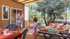 Une terrasse extérieure couverte, équipée d’une table, de chaises et d’un espace détente avec des chaises longues.