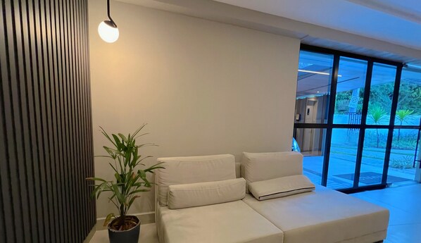 Una habitación moderna con un sofá blanco, una planta en maceta y un ventanal con vistas al exterior.