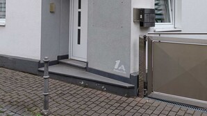 A modern building with a grey facade, a white door, and a small window with a curtain.