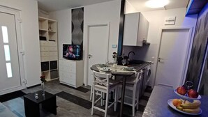A compact living space with a kitchenette, a dining area, and a seating area with a sofa and a coffee table.