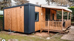 Une cabane en bois dotée d’une terrasse et d’un porche abrité.