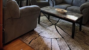 Un salon avec deux canapés gris, une petite table et un tableau encadré accroché au mur.