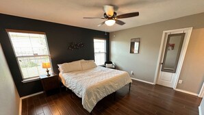A bedroom with a bed, a ceiling fan, a nightstand, and a window.