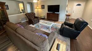A living room with a sofa, armchair, coffee table, and television.
