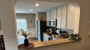 A kitchen with white cabinets, a microwave, a refrigerator, and a sink.