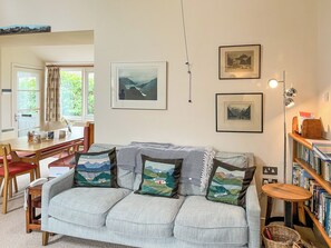A living room with a sofa, a dining table, and a bookshelf.
