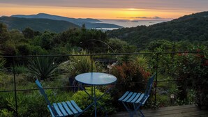 A terrace with a table and two chairs, overlooking a lush landscape and a sunset over the sea. - HOUSE & PRIVATE SWIMMING POOL SEA VIEW very quiet (Porto-Vecchio)