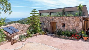 Un bâtiment moderne avec une façade en pierre, un jardin sur le toit et une vue sur la mer.