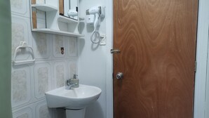 A bathroom with a white sink, a toilet, a wooden door, and a mirror with a towel rack. - Cabañas EcoSur-Chile  (Curacautin)