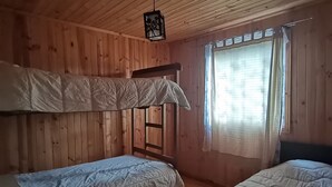 A wooden cabin room with two bunk beds, a ladder, and a window with curtains. - Cabañas EcoSur-Chile  (Curacautin)