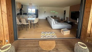 Ein modernes Wohnzimmer mit einer Couch, einem Esstisch und Stühlen. Es gibt einen Fernseher und einen Kamin.