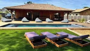 Ein Poolbereich mit Holzterrasse, Pool und drei Liegestühlen.