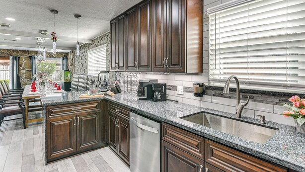 A modern kitchen with dark wood cabinets, granite countertops, and stainless steel appliances. - ~ 2 Blocks to Beach: Galveston Group Getaway! (Galveston)