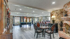 A spacious indoor area with a pool table, multiple seating arrangements, and a stone wall with a fireplace. - ~ 2 Blocks to Beach: Galveston Group Getaway! (Galveston)