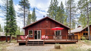 A rustic wooden cabin with a deck, surrounded by tall pine trees. - Home w/ Deck + Access to Tahoe Donner Amenities! (Truckee)