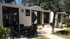 Una hilera de casas móviles con ventanas amplias y un patio con mobiliario exterior.