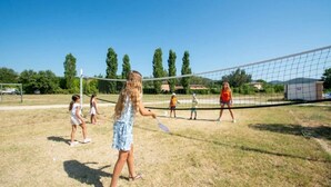 Un grupo de personas jugando voleibol en un campo cubierto de césped con una red.