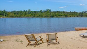 Une plage avec deux chaises en bois et un petit bateau sur le sable.