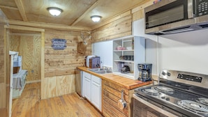 Une cuisine avec des murs en bois, un four à micro-ondes, une cuisinière et un évier.